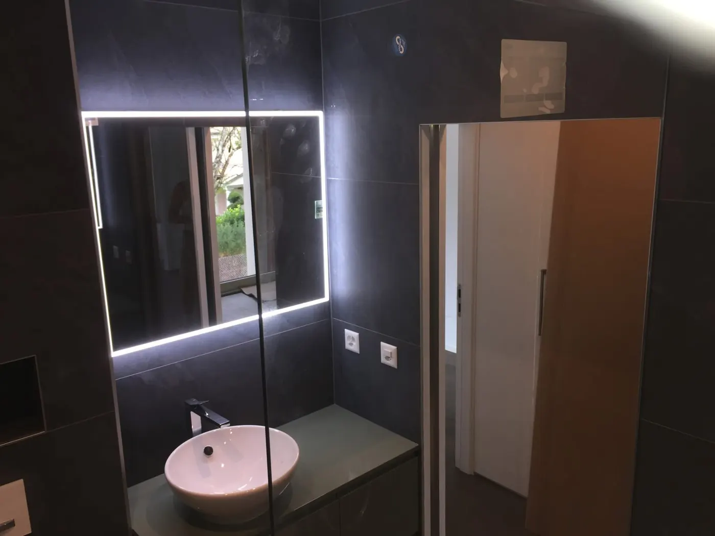Salle de bain rénovée en carrelage anthracite avec miroir lumineux, réalisation ZH Carrelage & Rénovation